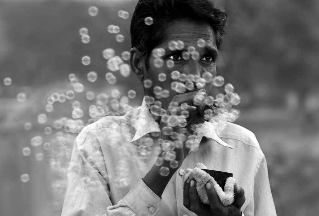 Blowing bubbles Indian man blowing bubbles in the street, India - stock photo