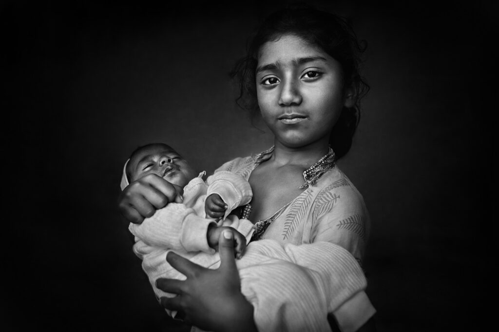 Girls Standing portrait of Indian girl hugging a baby, India - stock photo