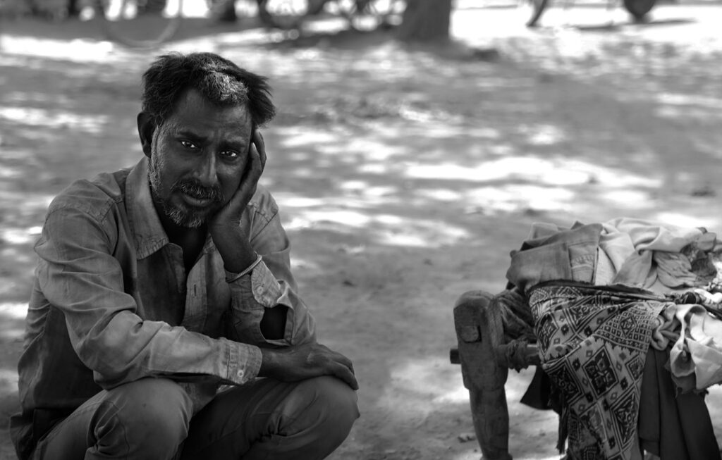 Homeless Indian Man Homeless Indian man crouching on the sidewalk - Stock photo